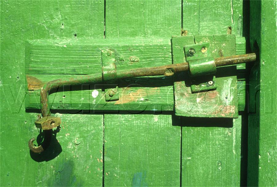 Detail of green painted wooden door and bolt fastener. / Location: Greece.
